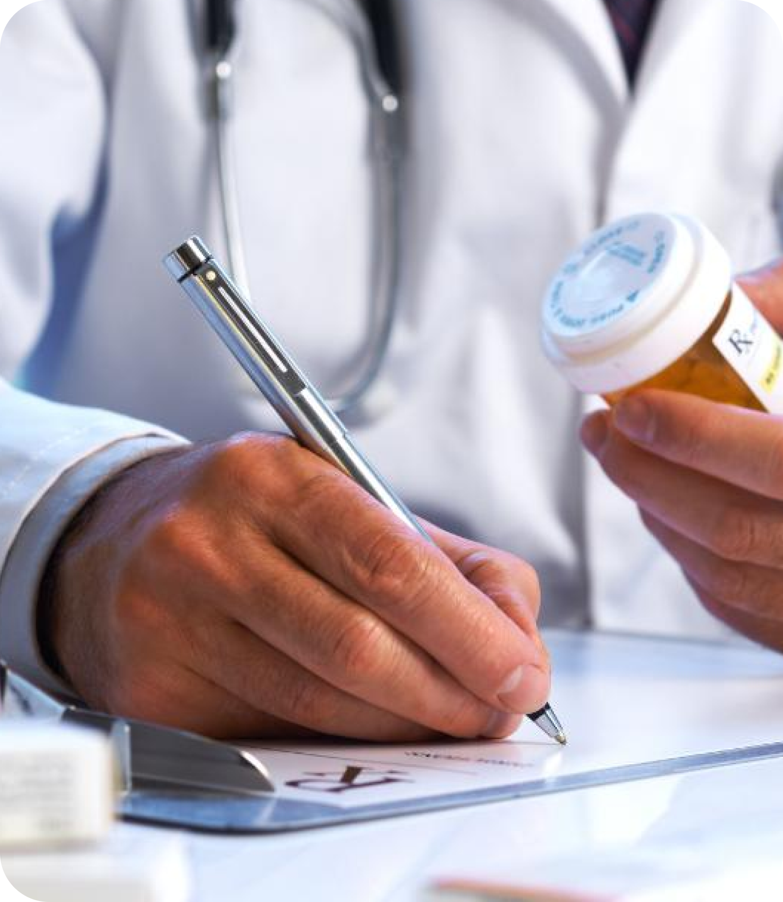 Doctor writing a prescription while holding a medication bottle