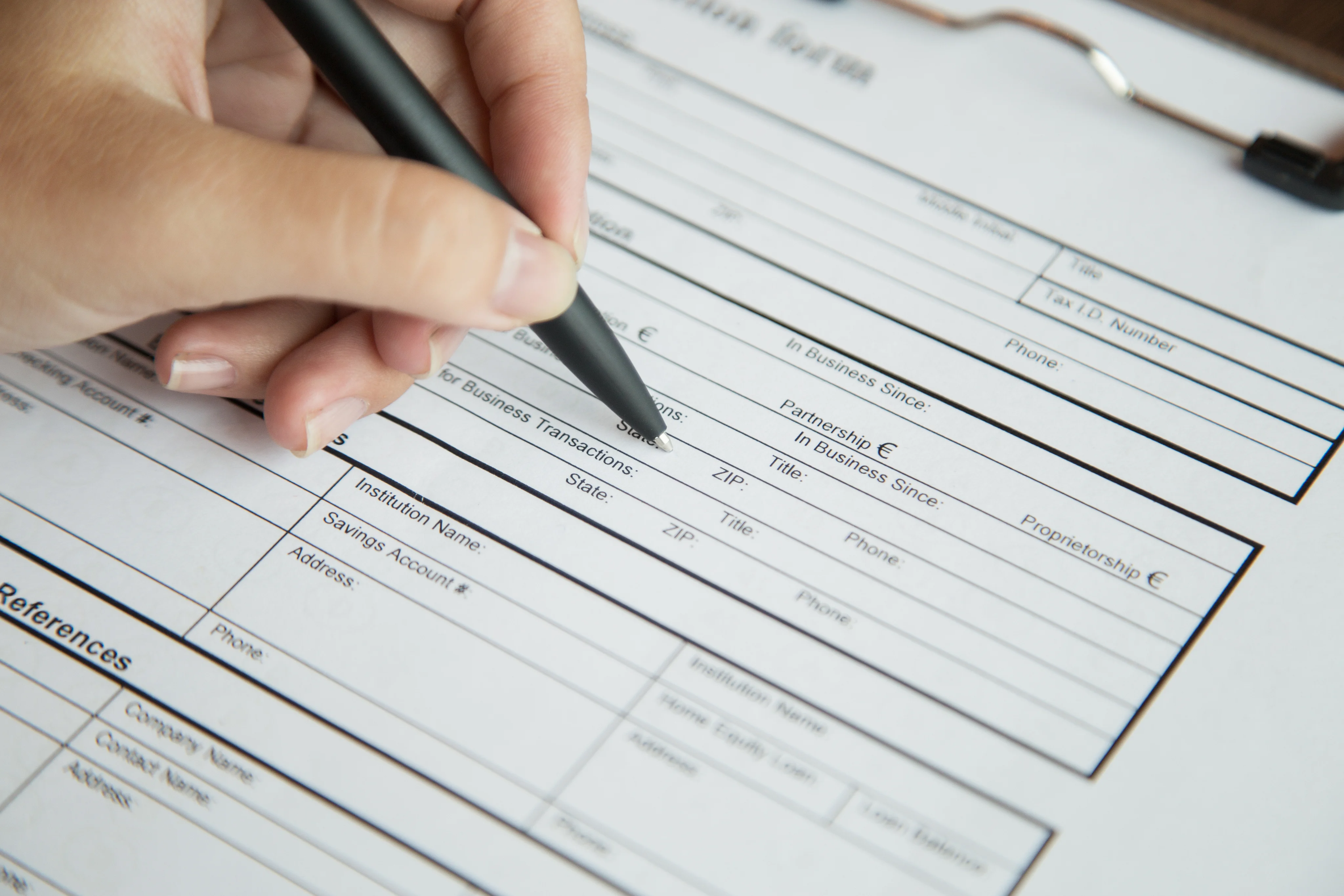 Hand filling out a referral form with a pen